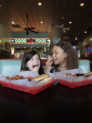 two girls eat burgers at dyers