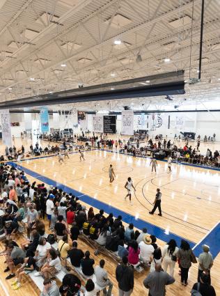 a team plays basketball at nike eybl while friends and family line the court