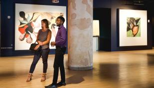two people stand in Crosstown Concourse art gallery looking at pieces