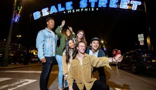 group of friends pose in front of beale street sign