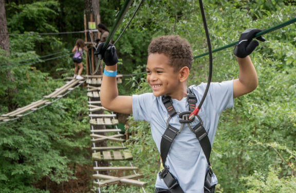 young boy walks across rope bridge